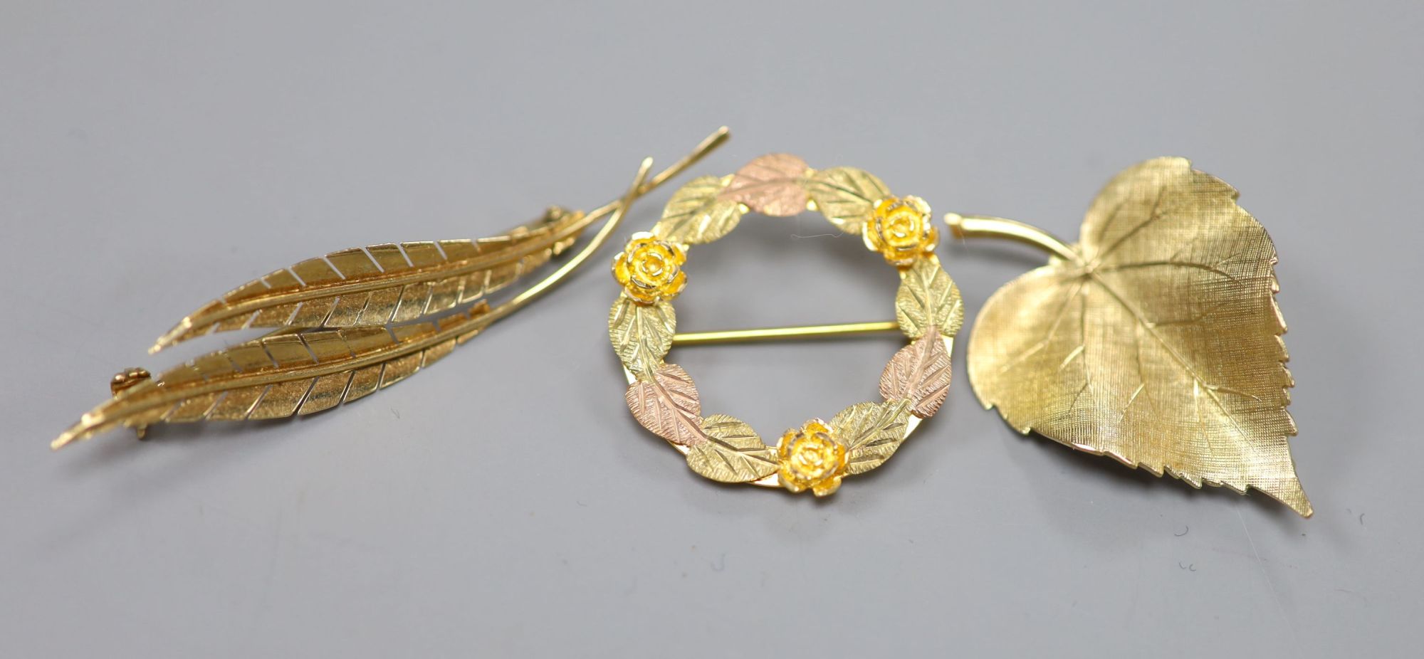 A 585 yellow metal double leaf brooch, 51mm a 9ct gold leaf brooch and a 10k tri-colour foliate wreath brooch (3)
